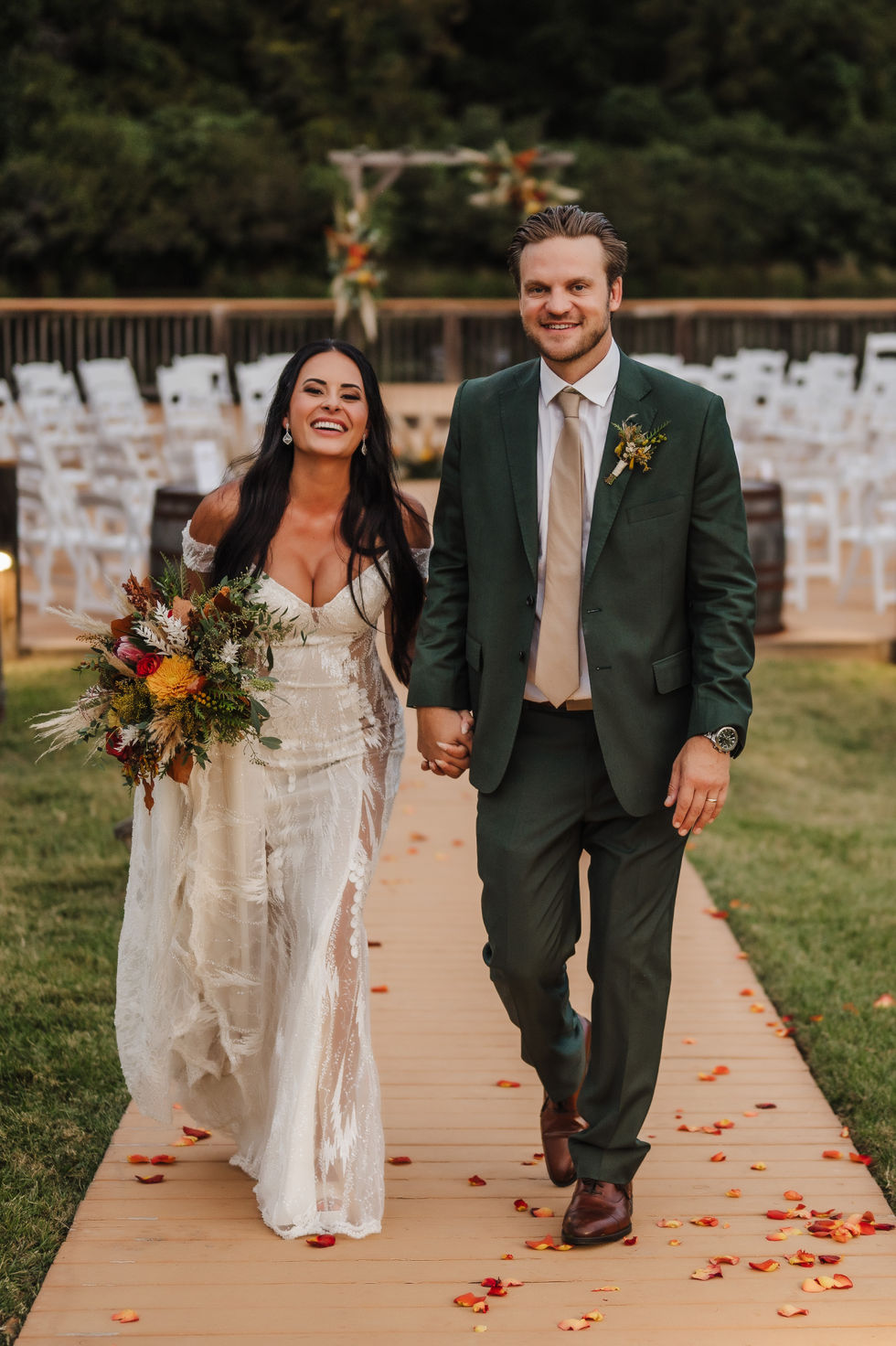 Bride and groom walking down a petal strewn aisle path