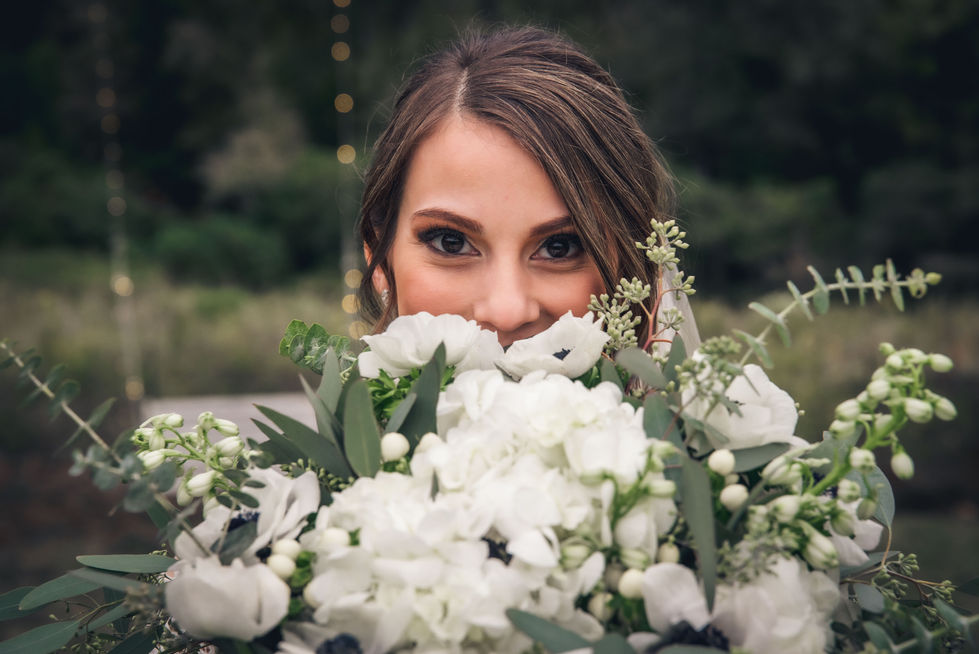 Close-up of the bride's face peeking over a white bouquet