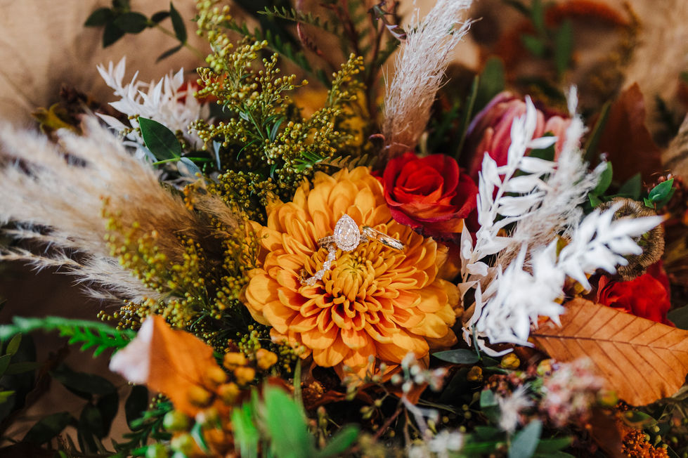 Close up of orange dahlia bouquet with engagement ring