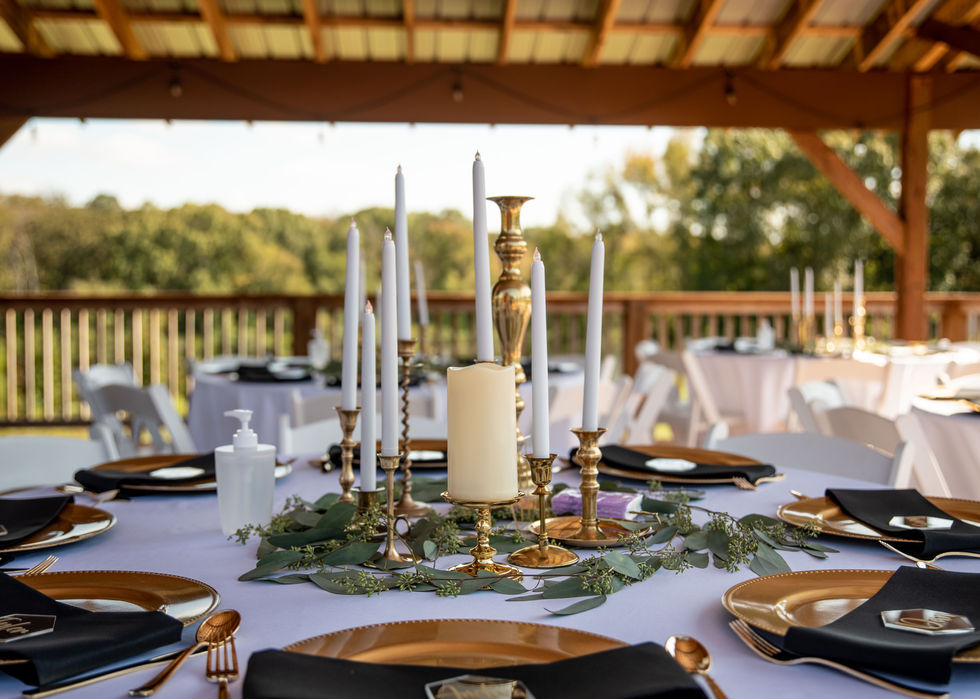 Wedding reception table with candles, greenery, and gold place settings