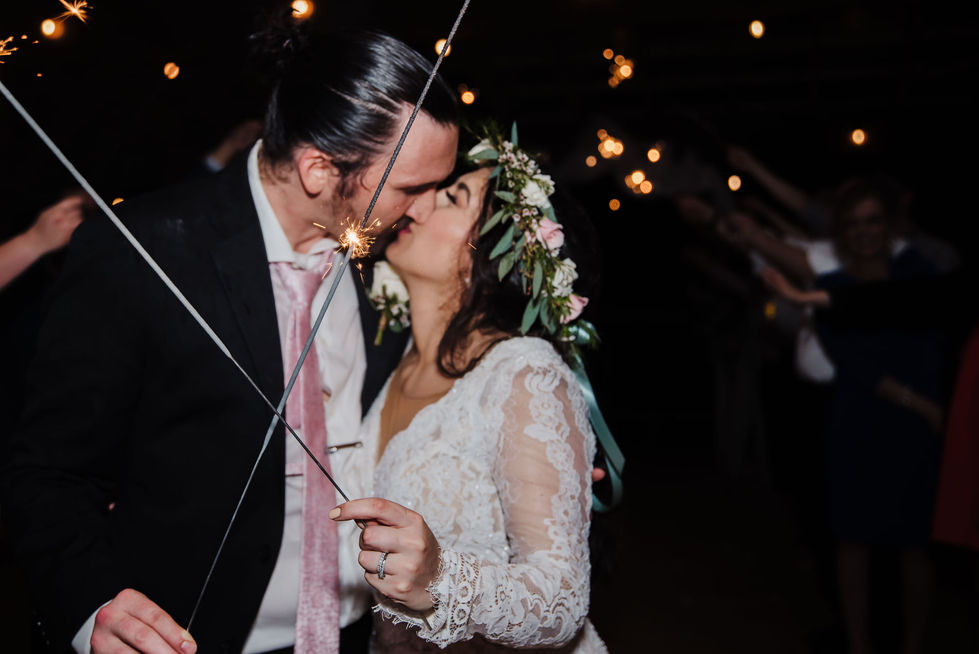 Bride and groom kissing under a sparkler send-off at night at Cedar Cove Ranch