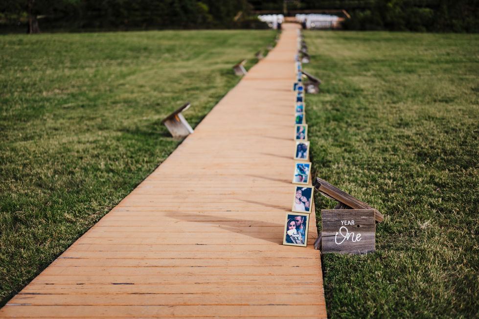 Wooden aisle path lined with signs leading to the ceremony