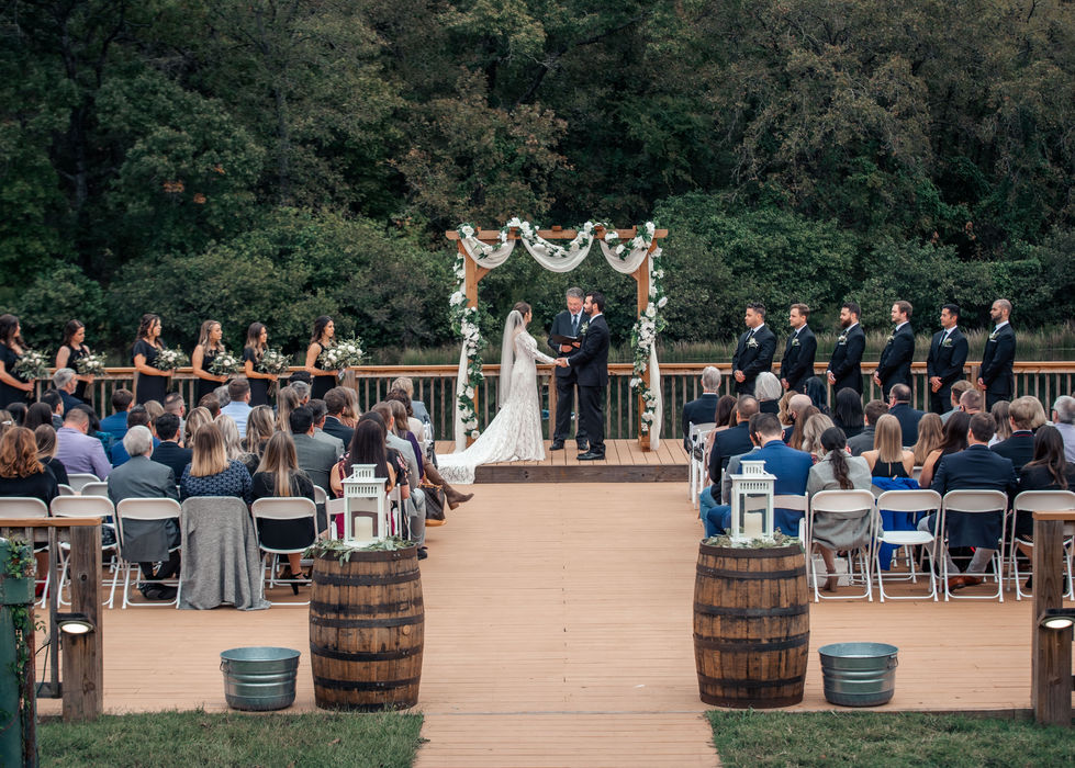 Wide view of the floral wedding ceremony arbor with the couple and officiant
