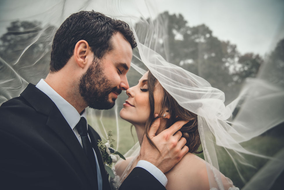 Close-up of bride and groom with the veil flowing around them