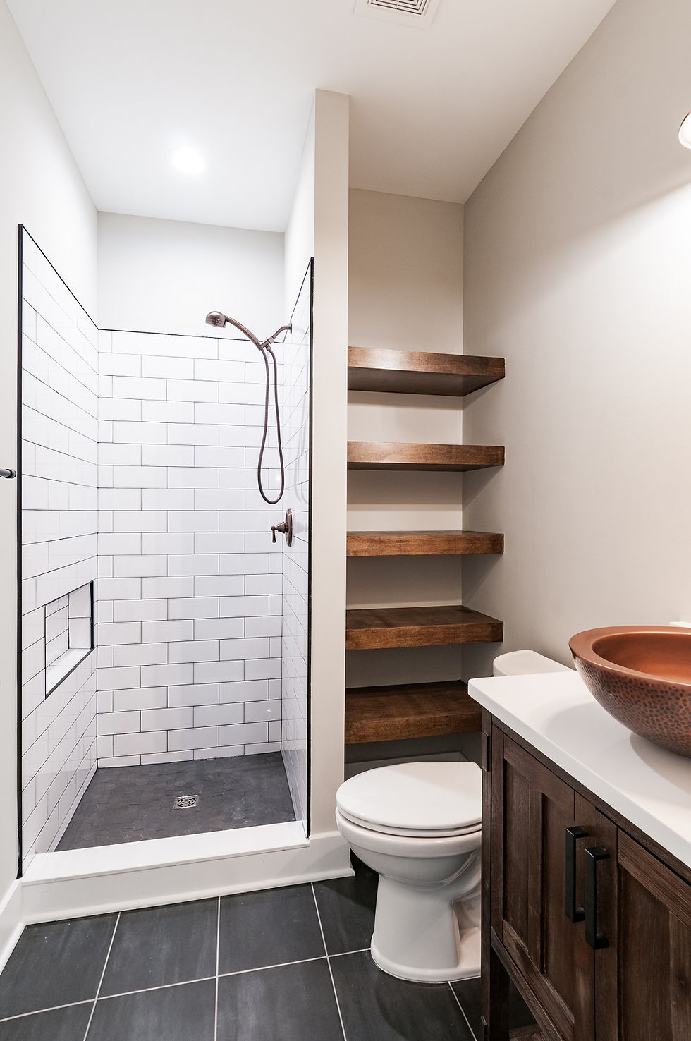 Rustic modern powder room with subway tile shower, floating wood shelves, and copper vessel sink