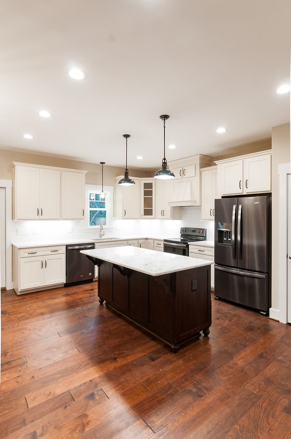 Black and white kitchen with black appliances, and stained hardwood-look floors