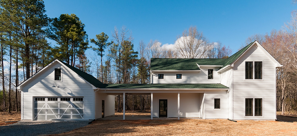 Modern spin on traditional farmhouse with green shingle roof, black windows and covered walkway to detached garage