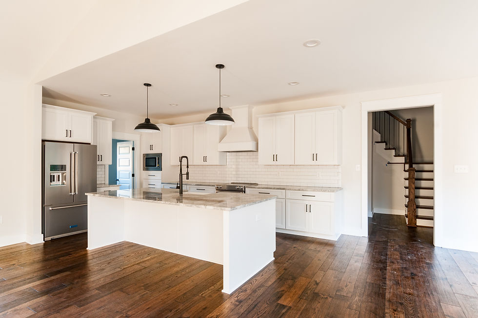 Modern white kitchen with large island, pendant lights, and stainless steel refrigerator