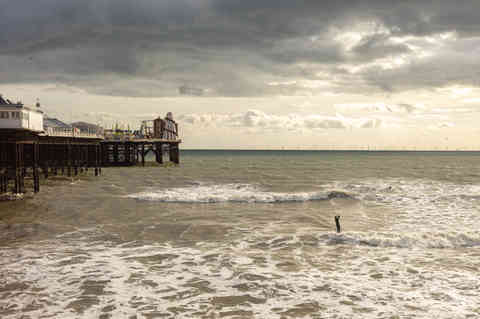 Surfer riding a wave under Brighton Palace Pier — fine art print by Alessandro Intini