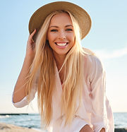 Young attractive smiling blond woman in white shirt and hat joyfully looking in camera wit