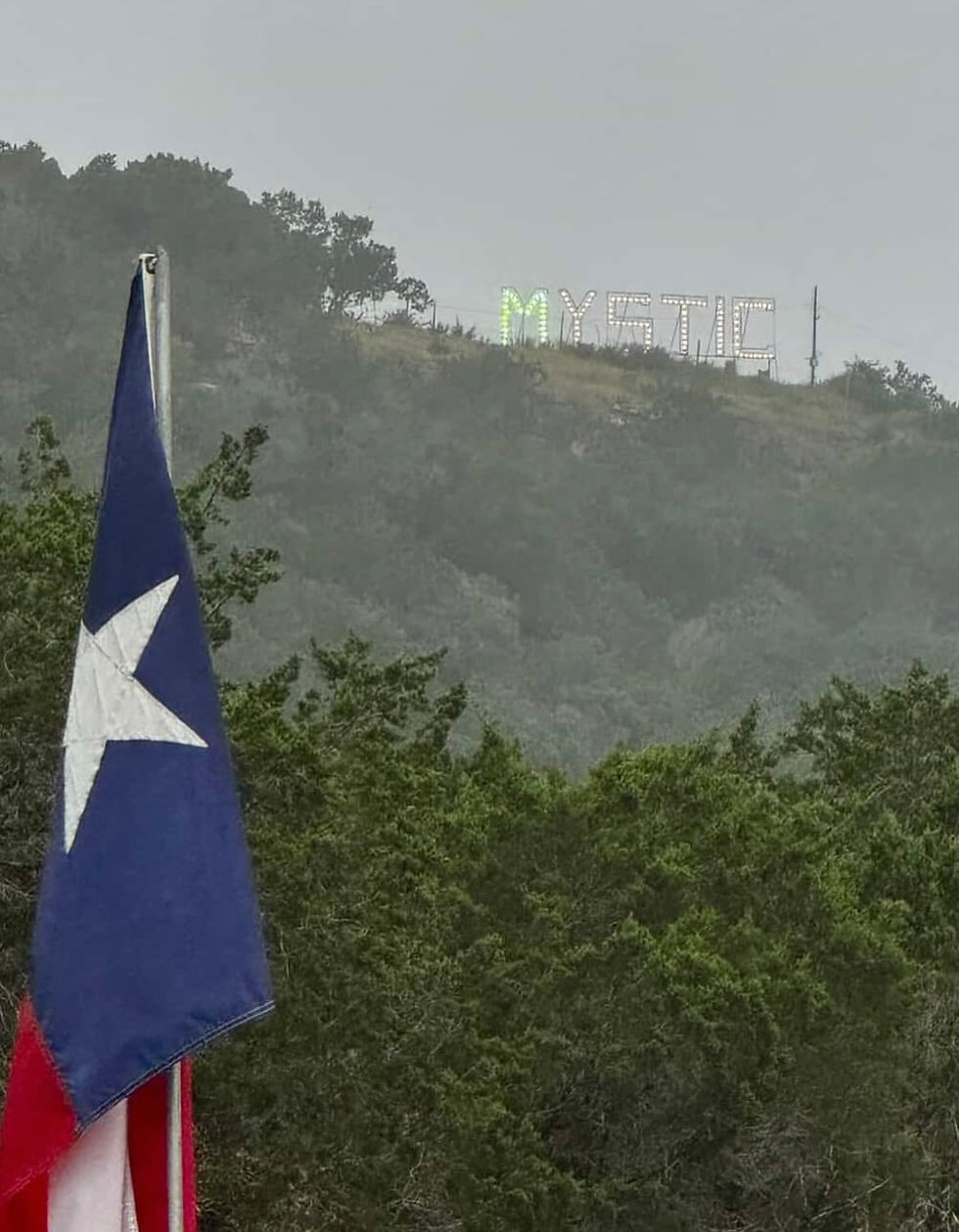Photo of the Mystic sign, with 27 green bulbs in the "M" to honor the 27 lost loved ones. Each night, the husband of the camp nurse drives up the hill to turn on the generator, so the Mystic sign can be illuminated.