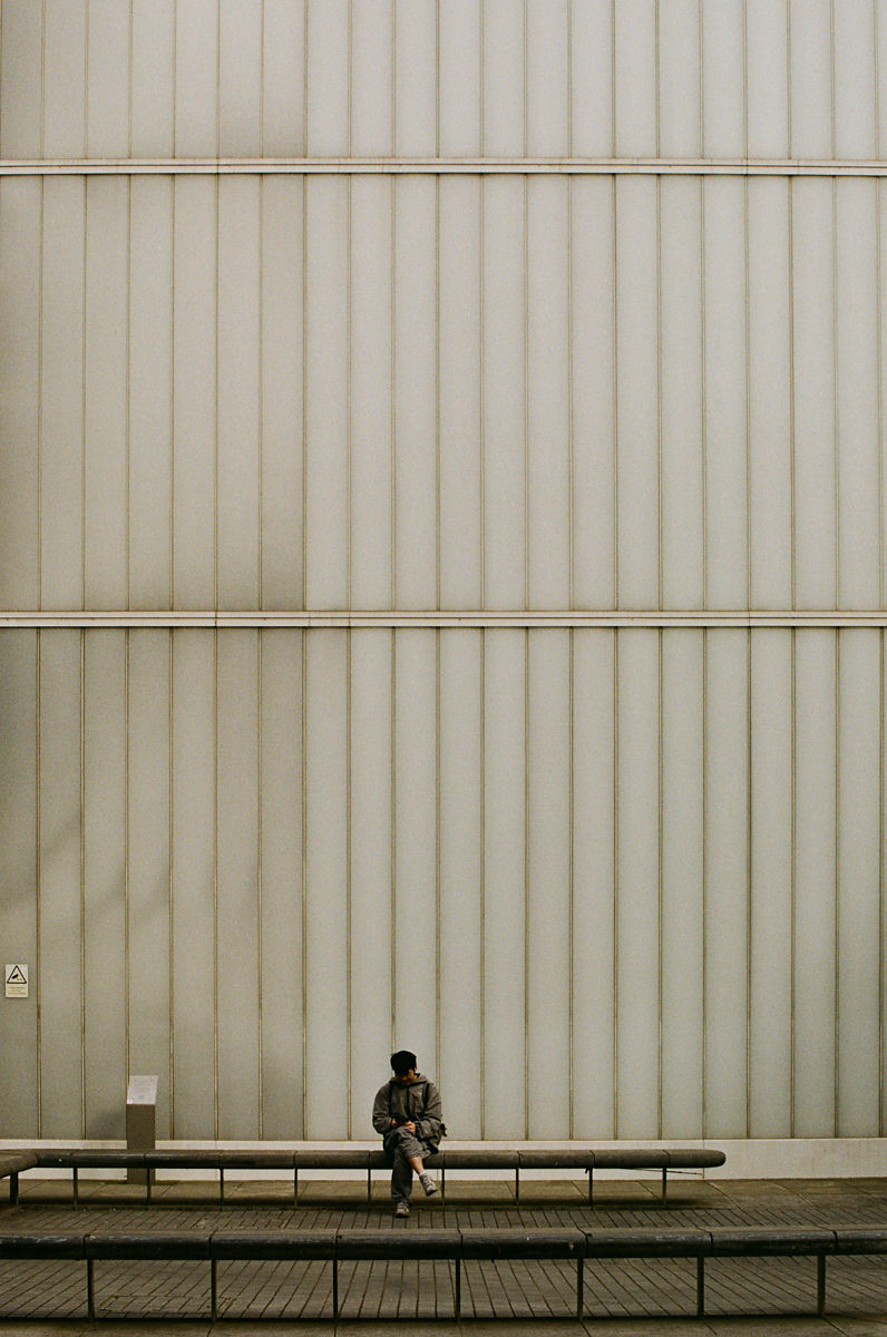 London street photography of a person by a fluted wall