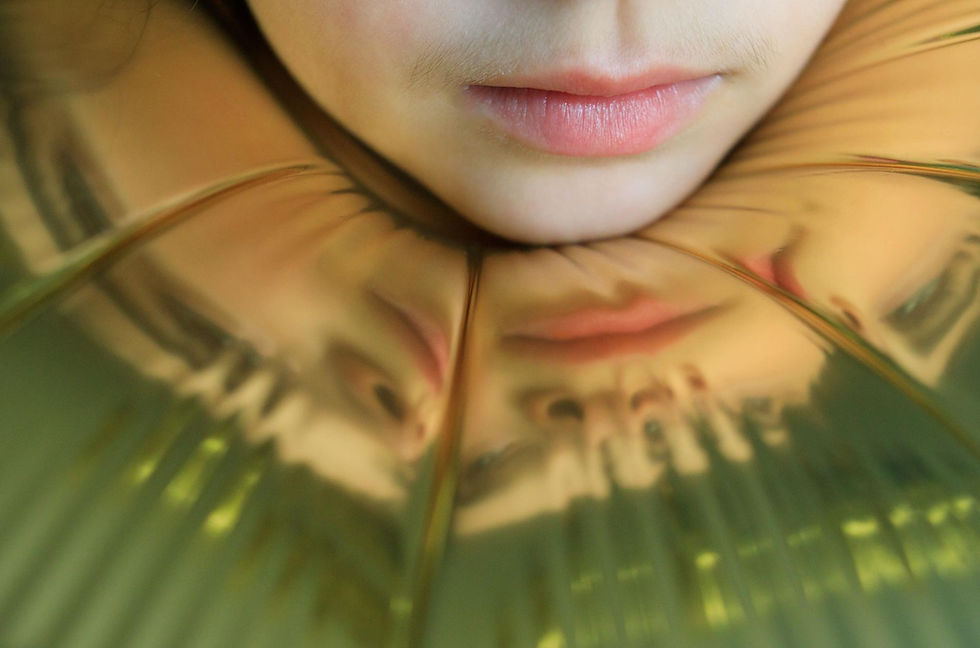 Chin resting on a gold balloon reflecting a person's face