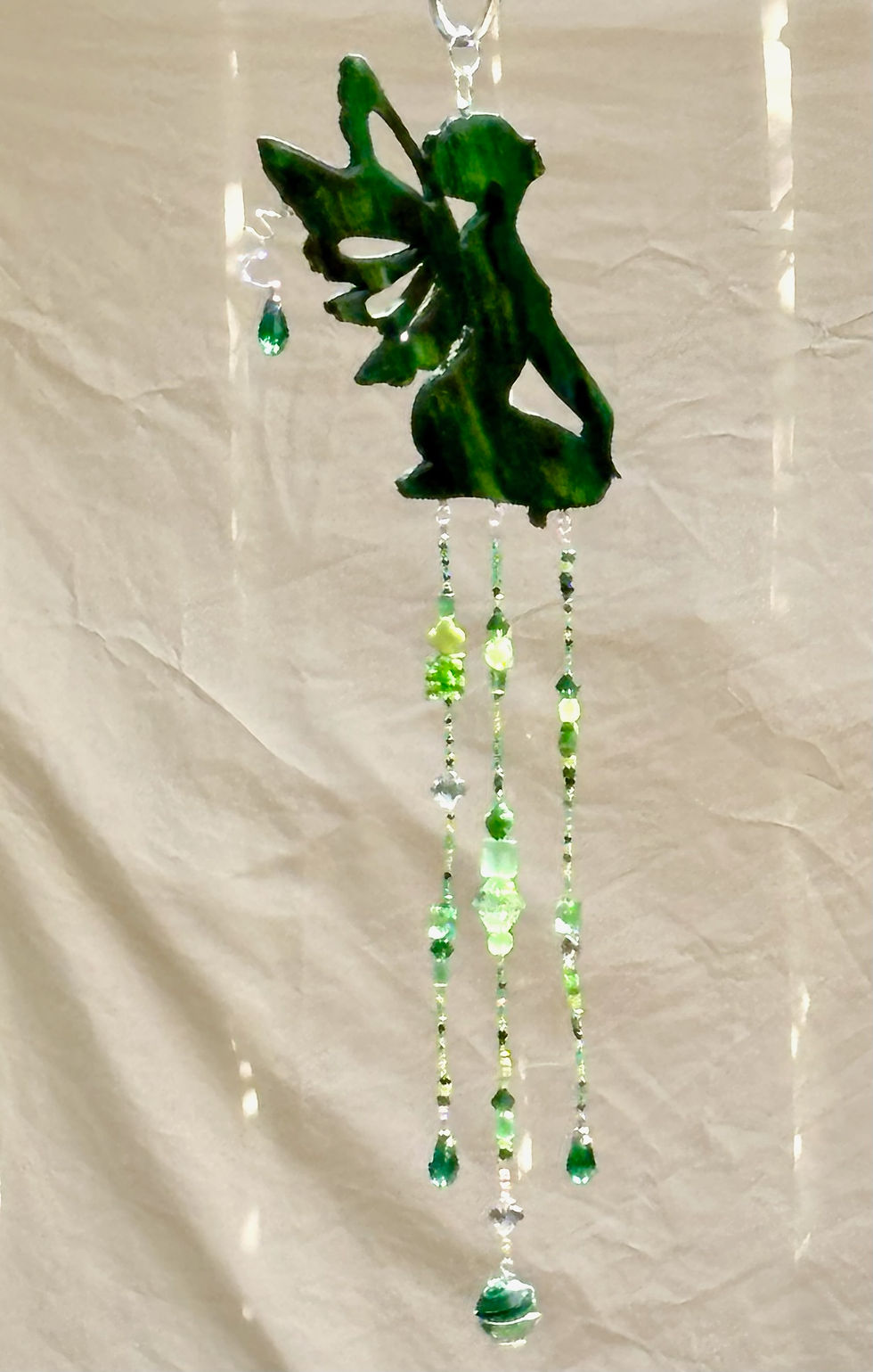 Miniature : Green fairy decoration with hanging beads against a white draped background
