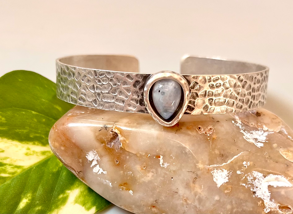 Miniature : Silver cuff bracelet with pear gemstone set on a natural stone background