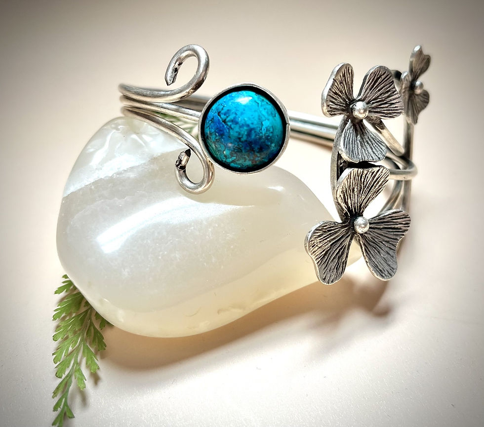 Miniature : Silver bracelet with blue gem and flower design resting on a white stone