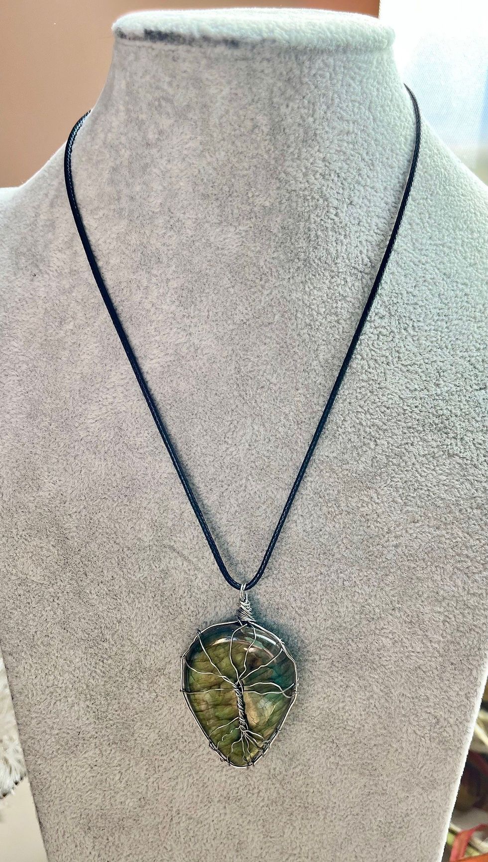 Miniatura: Green pendant necklace displayed on a mannequin, with a dark cord.