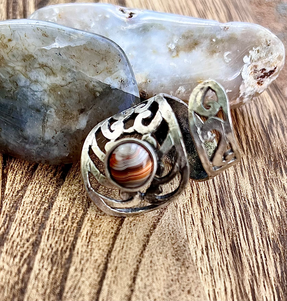 Miniatura: Silver ring with a brown stone, sitting on a wooden surface.
