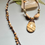 Thumbnail: Handmade necklace with natural stone pendant and beaded cord, earthy tones.