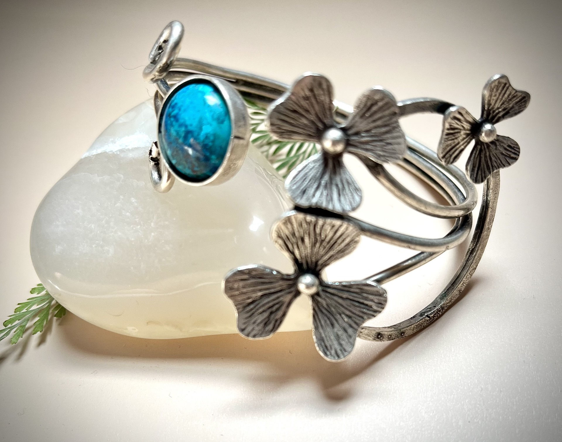 Silver bracelet with turquoise stone, floral accents, and a white background.