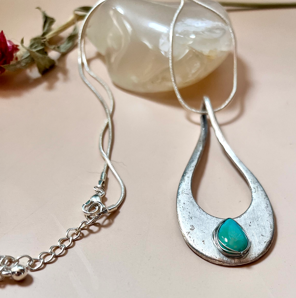 Miniatura: Silver teardrop pendant necklace with turquoise stone against a pink backdrop.