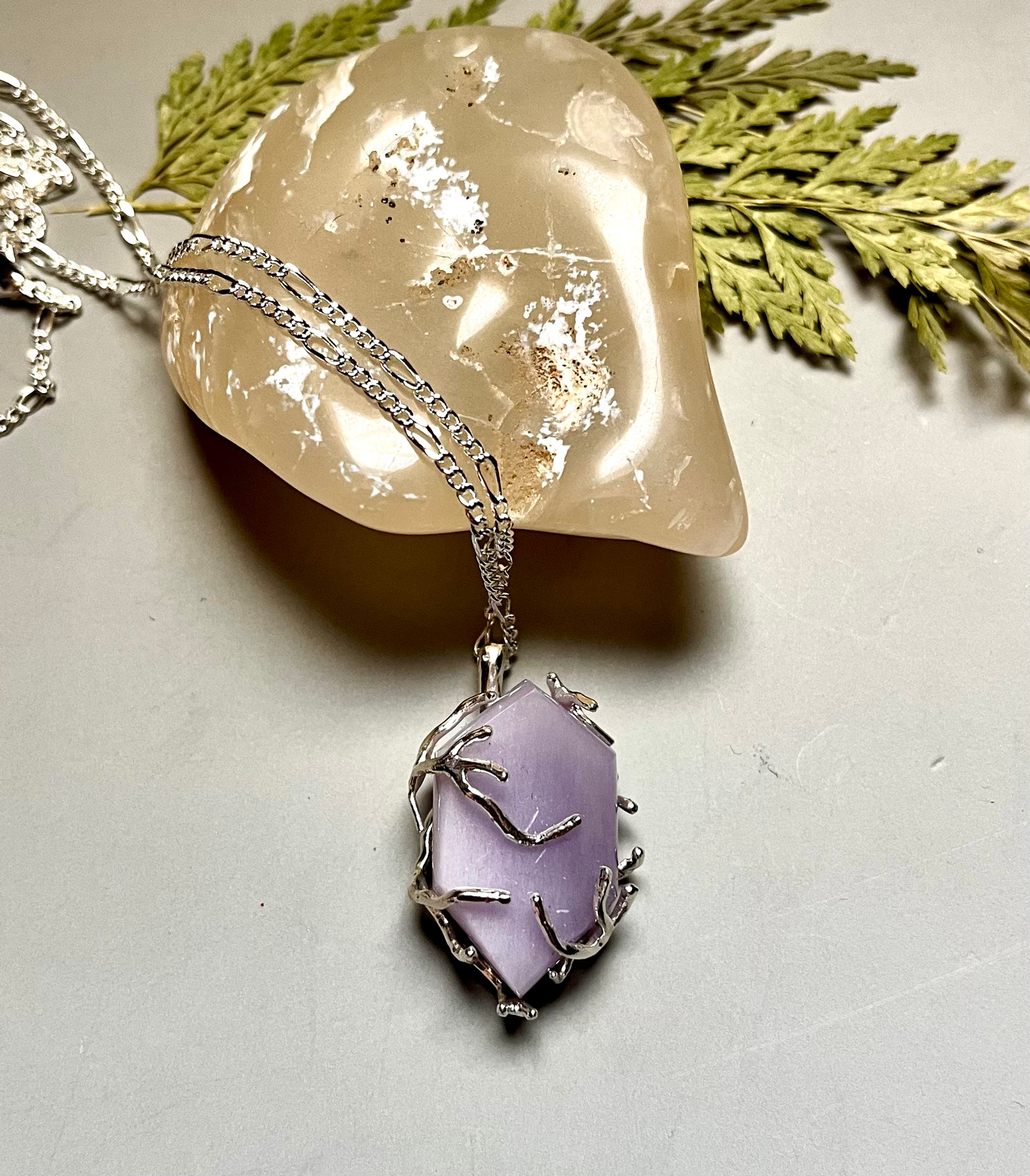 Elegant Yttrium Fluorite Pendant Necklace with a light purple stone on display.
