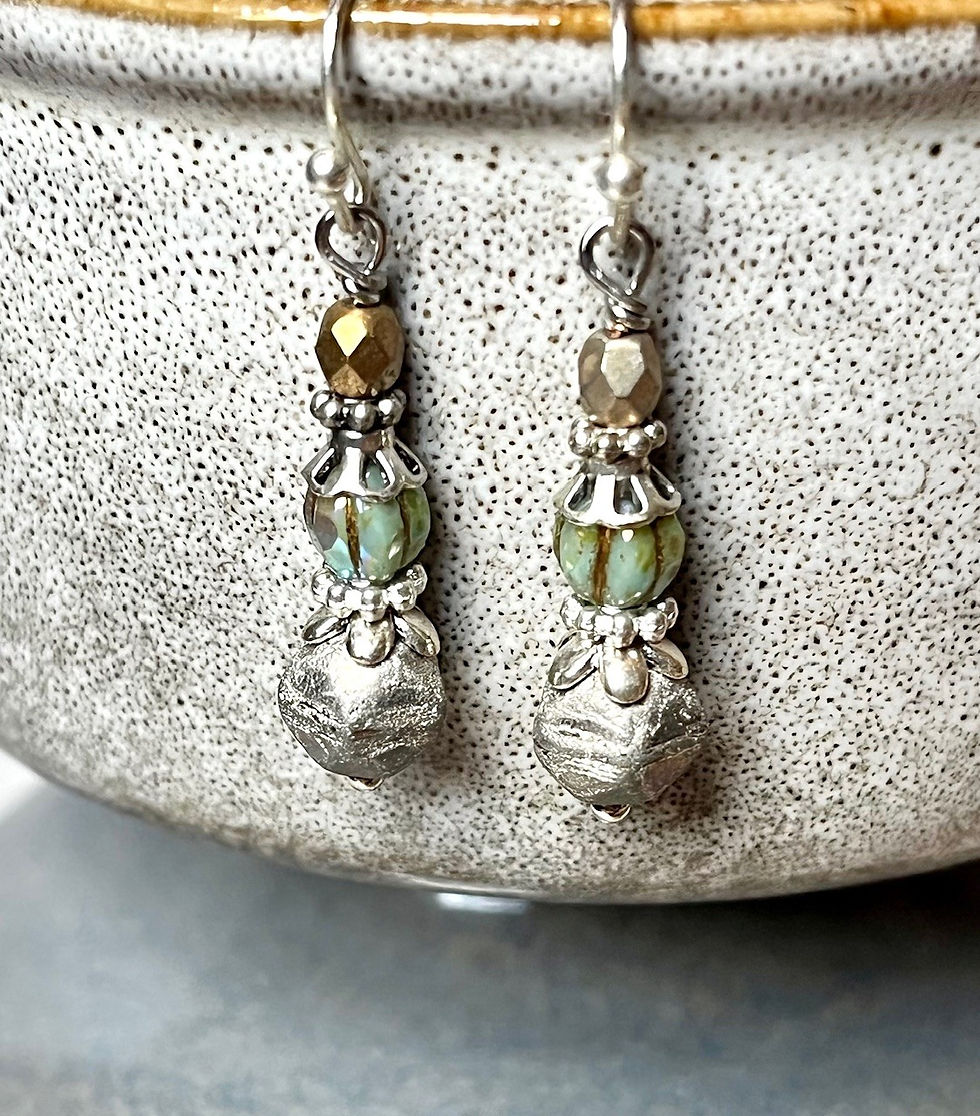 Miniatura: Dangling earrings with silver and gold beads on a ceramic edge.