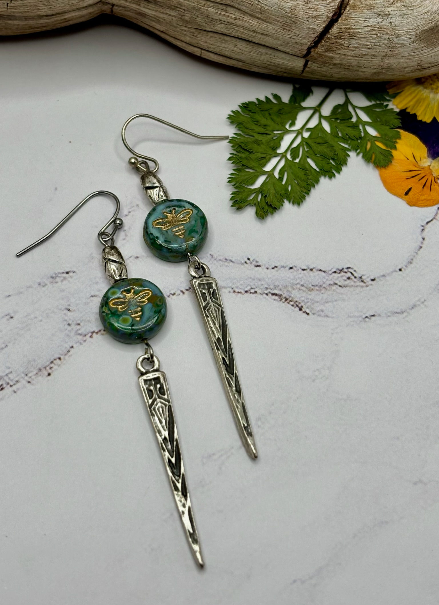 Elegant earrings with green beads and silver spikes, jewelry display.