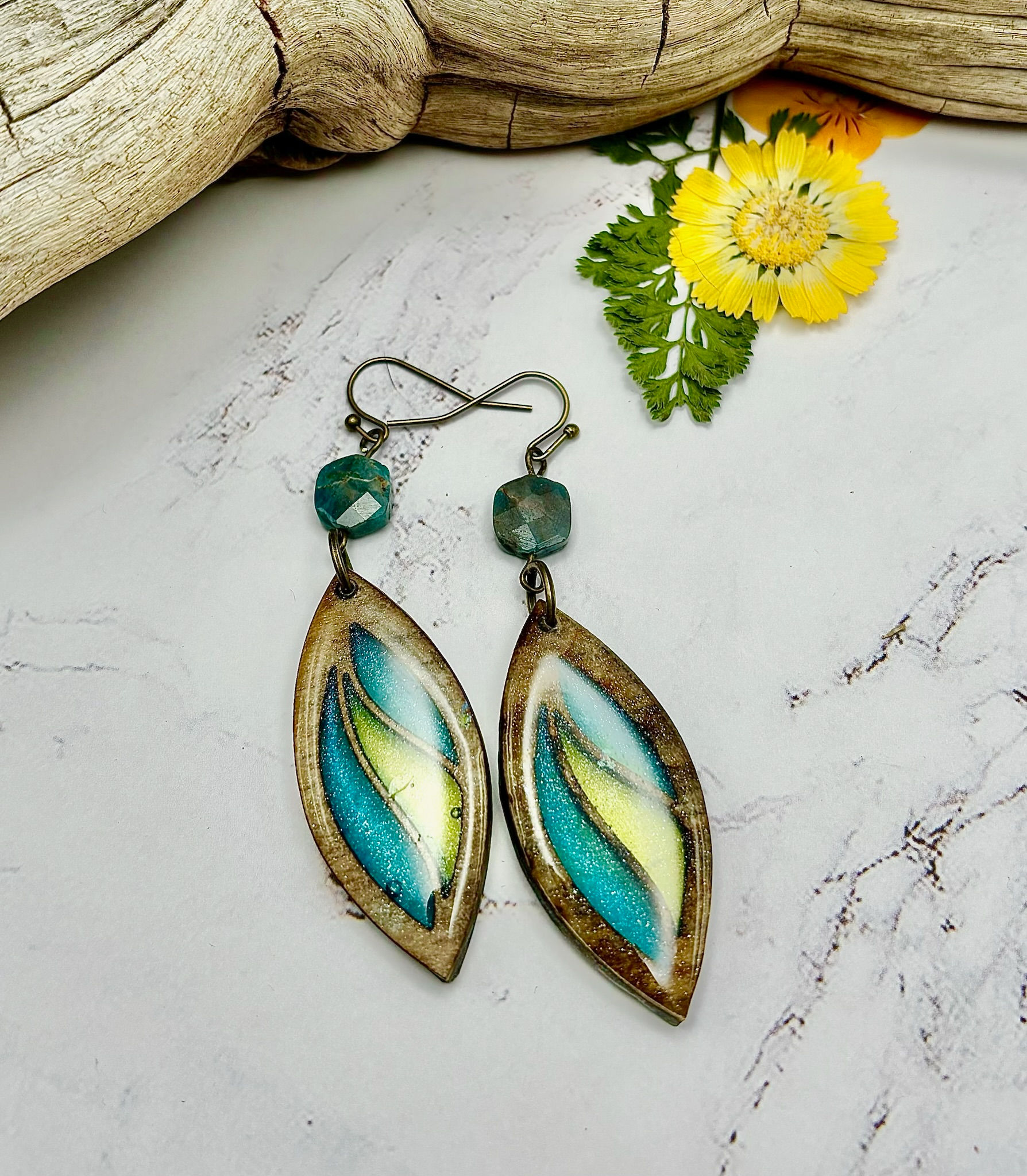 Elegant earrings with turquoise and yellow design, with a flower background.