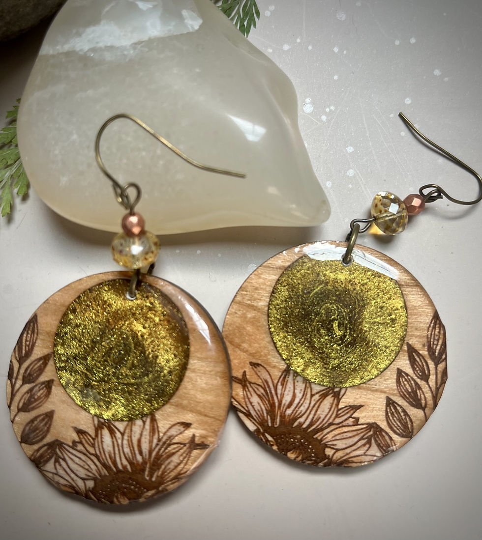 Miniatura: Wooden sunflower earrings with gold accents dangle on a white surface.