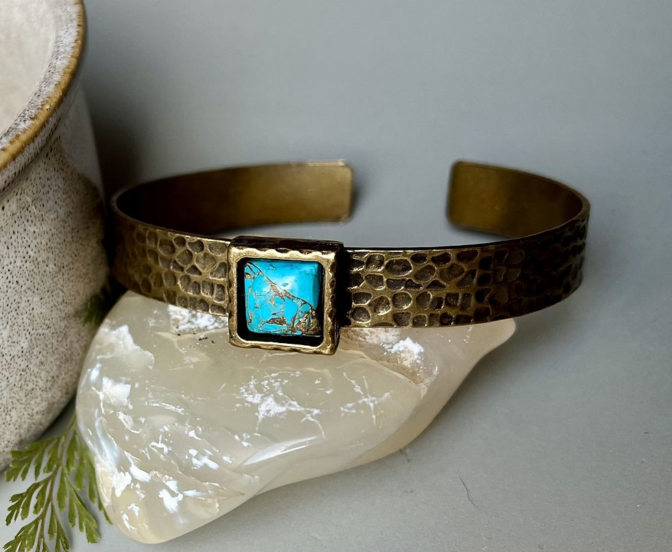 Miniature : Textured copper bracelet with turquoise stone, resting on a white stone.