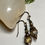 Thumbnail: Elegant earrings with dangling gold and brown beads on white background.