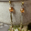 Thumbnail: Close-up of dangle earrings with amber beads and intricate floral designs.