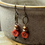 Thumbnail: Floral earrings hang from a neutral pot with red flower details and beads.