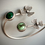 Thumbnail: Silver bracelet with green gemstones and flower details on gray background.