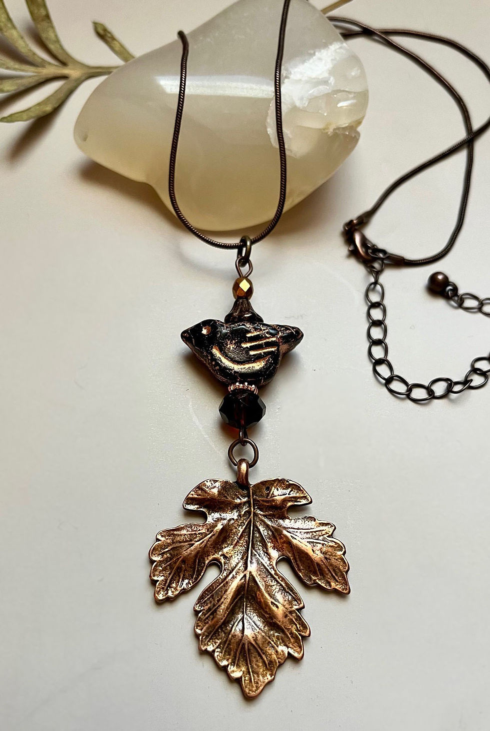 Miniature : Copper leaf pendant necklace hanging on a black cord with beads.