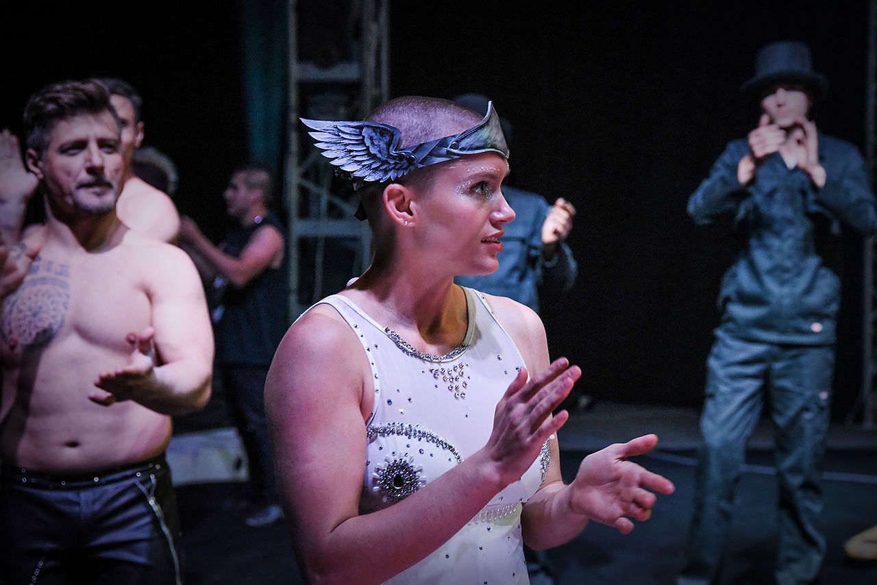 Artiste du Cirque Infernal avec coiffe ailée applaudissant