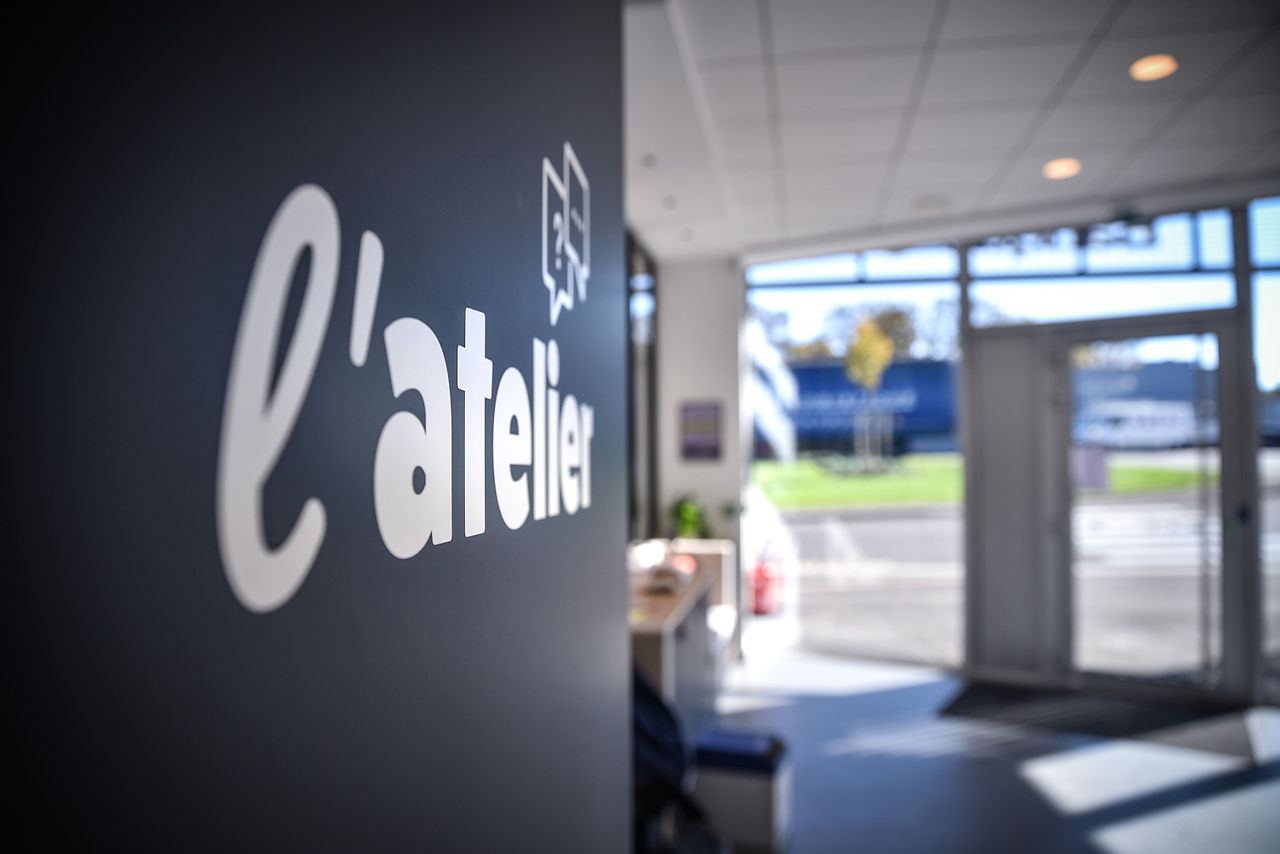 Enseigne L'Atelier dans une agence Banque Courtois rénovée.