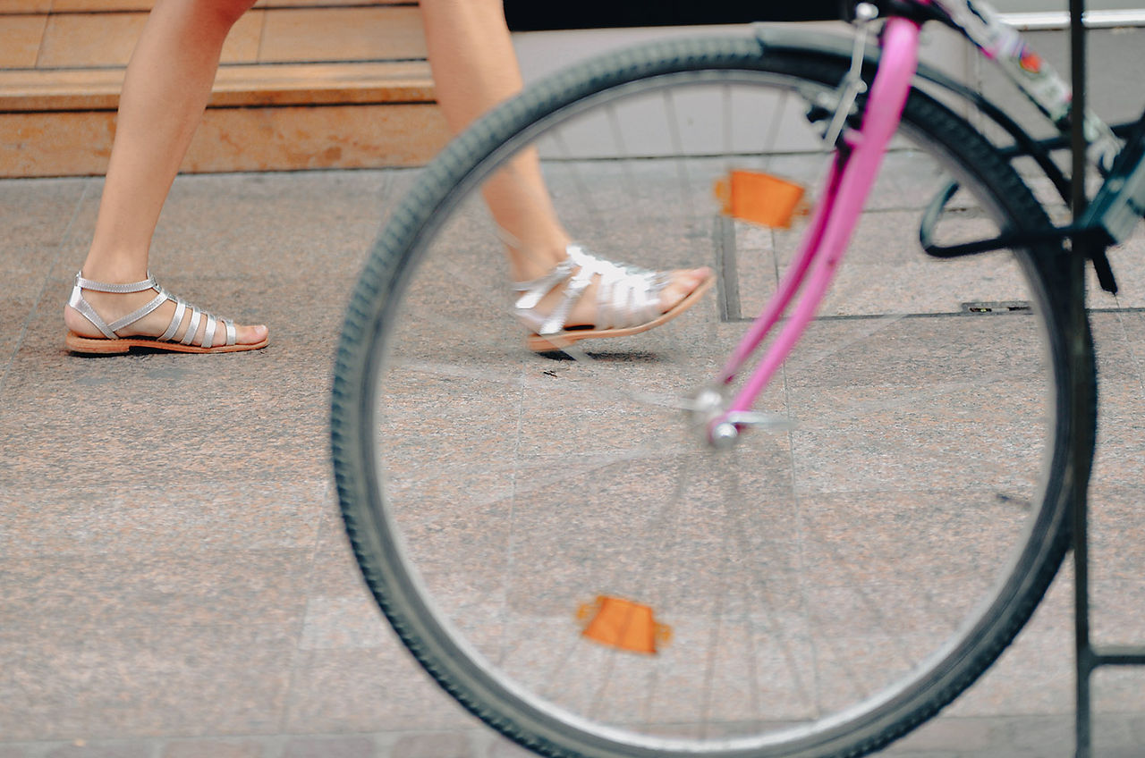 Gros plan d'une roue de vélo rose et d'une personne qui marche.