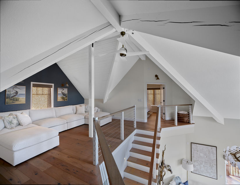 A-frame interior with a wood staircase, open loft and exposed white beams