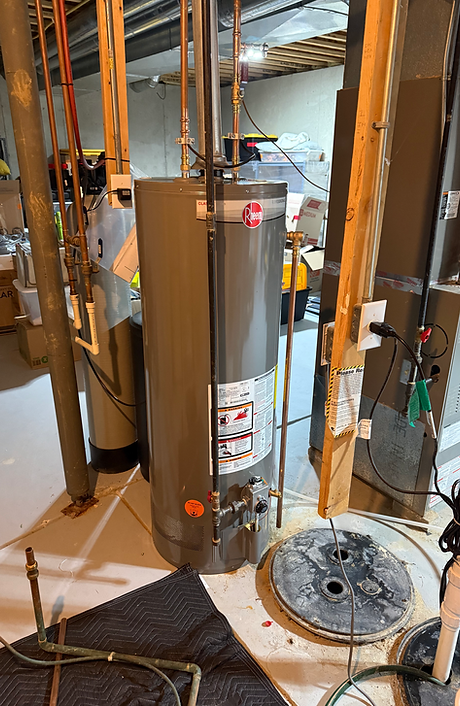 Rheem gas water heater in an unfinished basement next to a sump pit