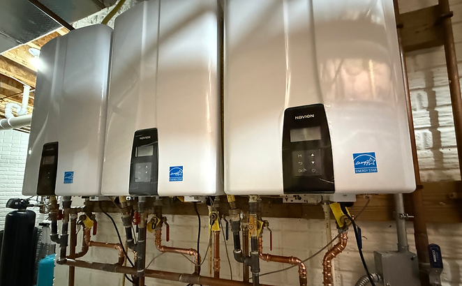 Row of wall-mounted tankless water heaters with copper water and gas piping