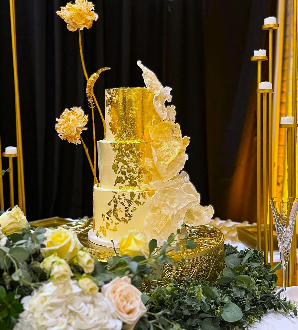 An elegant three-tiered wedding cake with gold leaf in the icing
