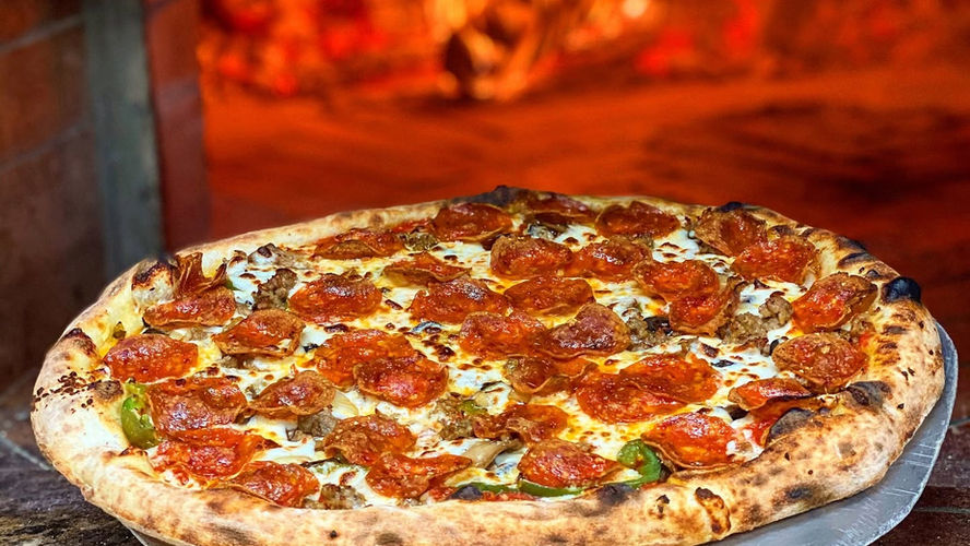 A large pepperoni pizza sits in front of a pizza oven at Pizzas & Cream
