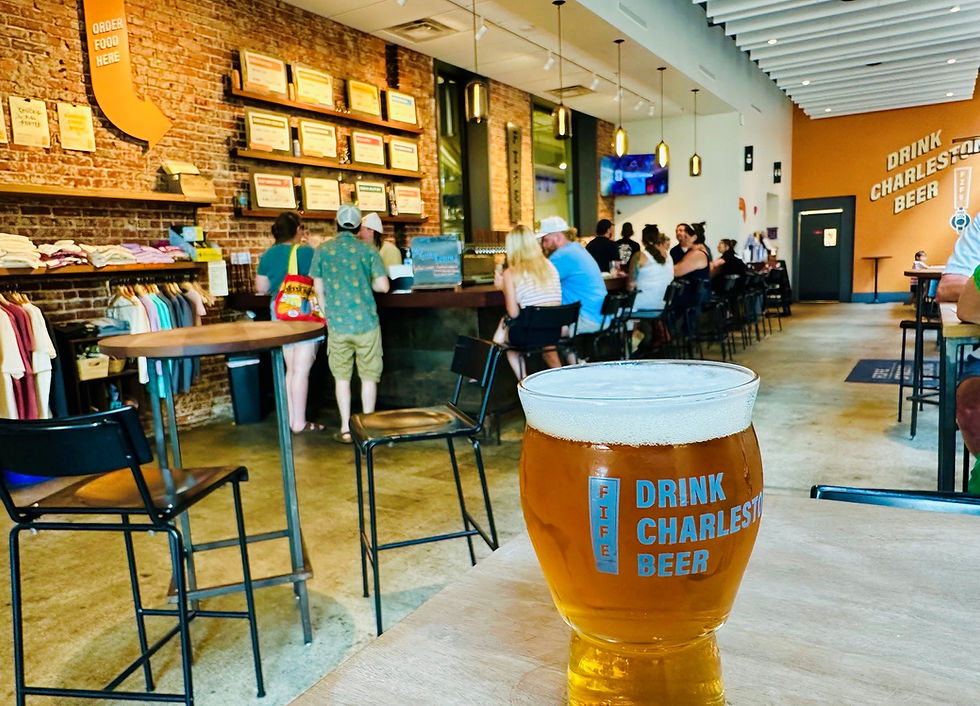 A pint of beer sits on a table with a taproom in the background at Fife Street Brewing in Charleston