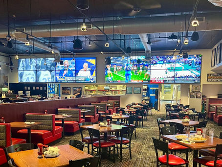 A sports bar and grill filled with tables and large TV screens