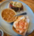 A plate filled with meatloaf topped with crispy fried onions, with baked beans and potato salad on the side