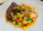 A plate of braised short ribs with colorful vegetables and a creamy sauce