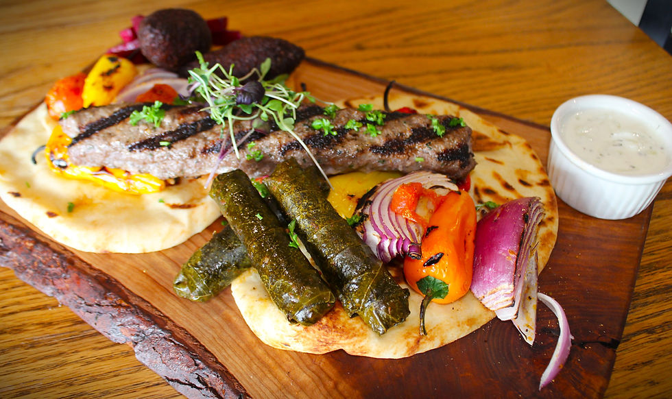 A wooden platter piled with samples of Middle Eastern dishes