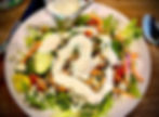 Plate of salad covered in ranch dressing